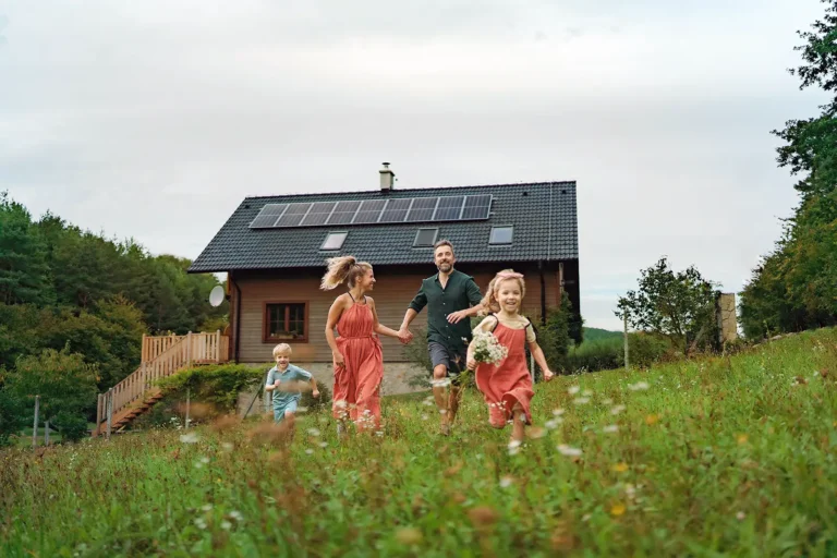 Familie auf Wiese und im Hintergrund Haus mit Photovoltaikanlage