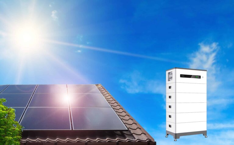 GoodWe Batteriespeicher und links daneben ein Hausdach mit Solarmodulen. Im Hintergrund blauer Himmel mit Sonne.