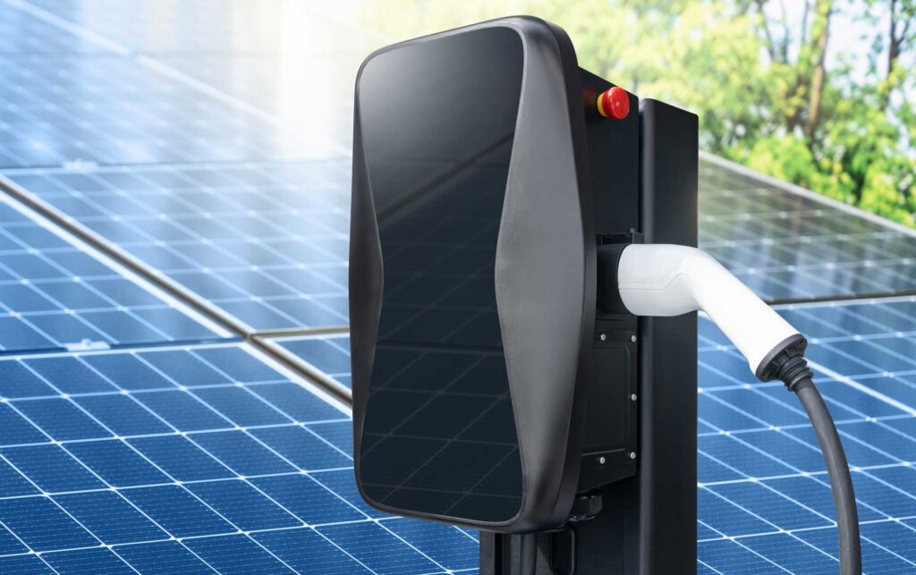 Wallbox mit Solarmodulen im Hintergrund