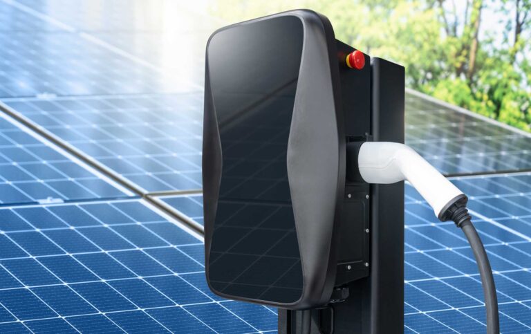 Wallbox mit Solarmodulen im Hintergrund