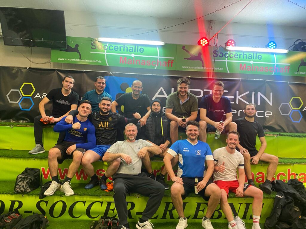 Teambild von naturwaerme Mitarbeiter auf Bänken bei Indoor Fussballspiel.