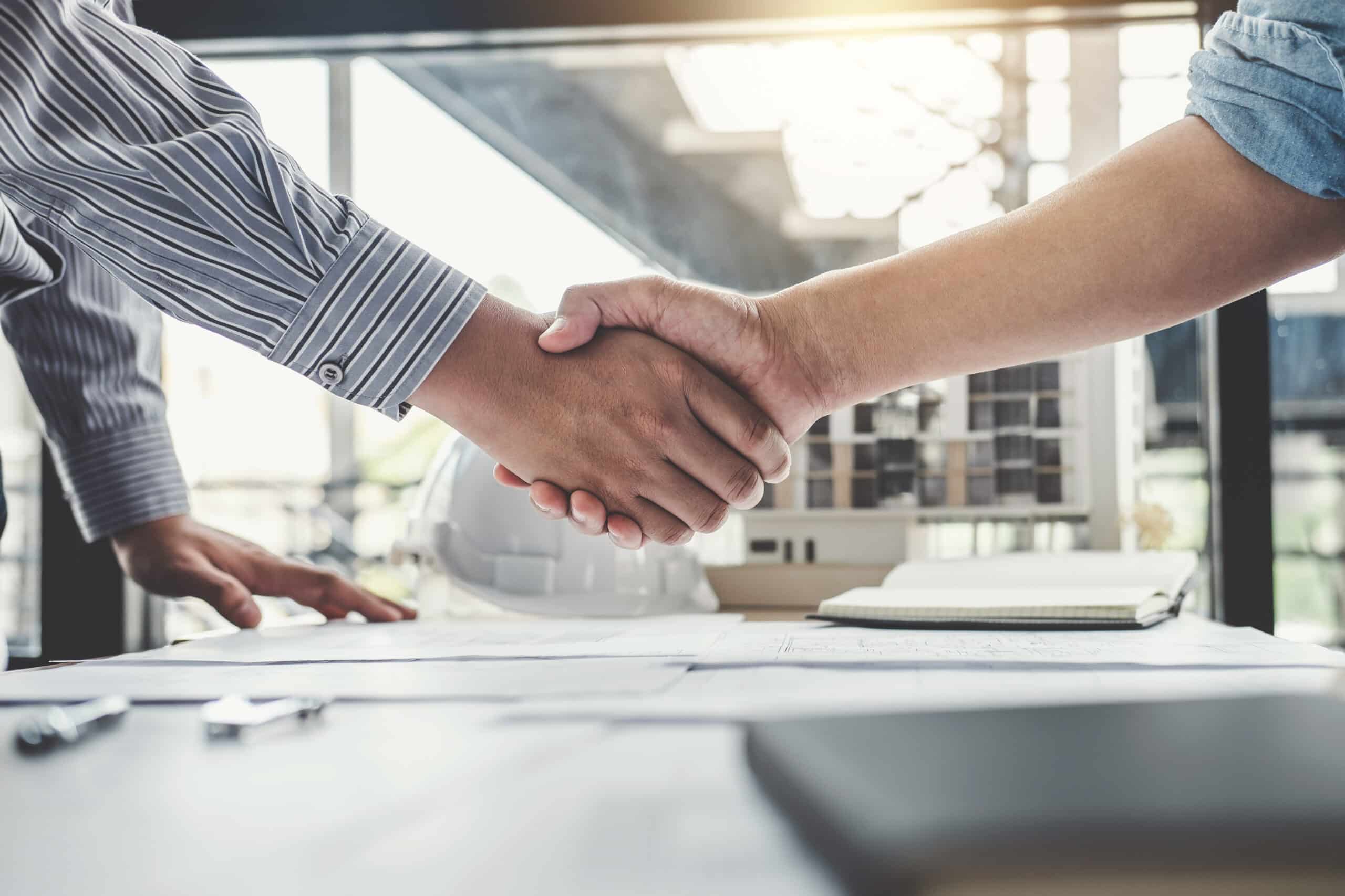 Zwei Menschen geben sich die Hände in einem Büro
