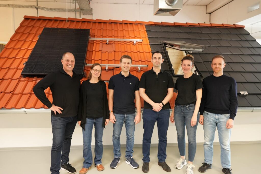 sechs Energieberater stehen vor Musterdach in Ausstellung
