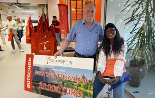 Mann mit Frau hält Scheck im Wert von 25.000 Euro einer Photovoltaikanlage in den Händen