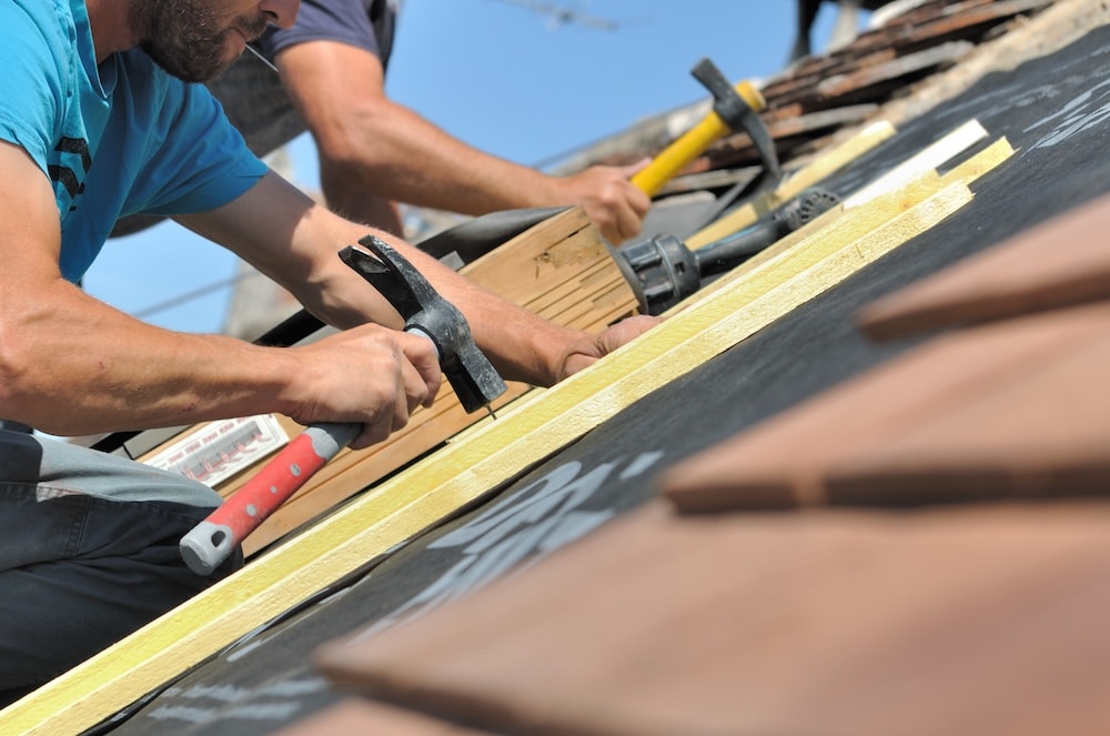 Handwerker arbeiten mit Hämmern auf Dach