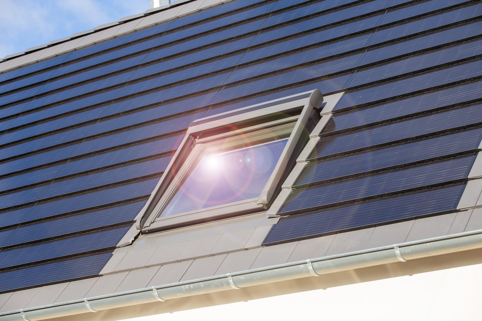 Dachfenster an einem Einfamilienhaus mit Solardachziegeln.