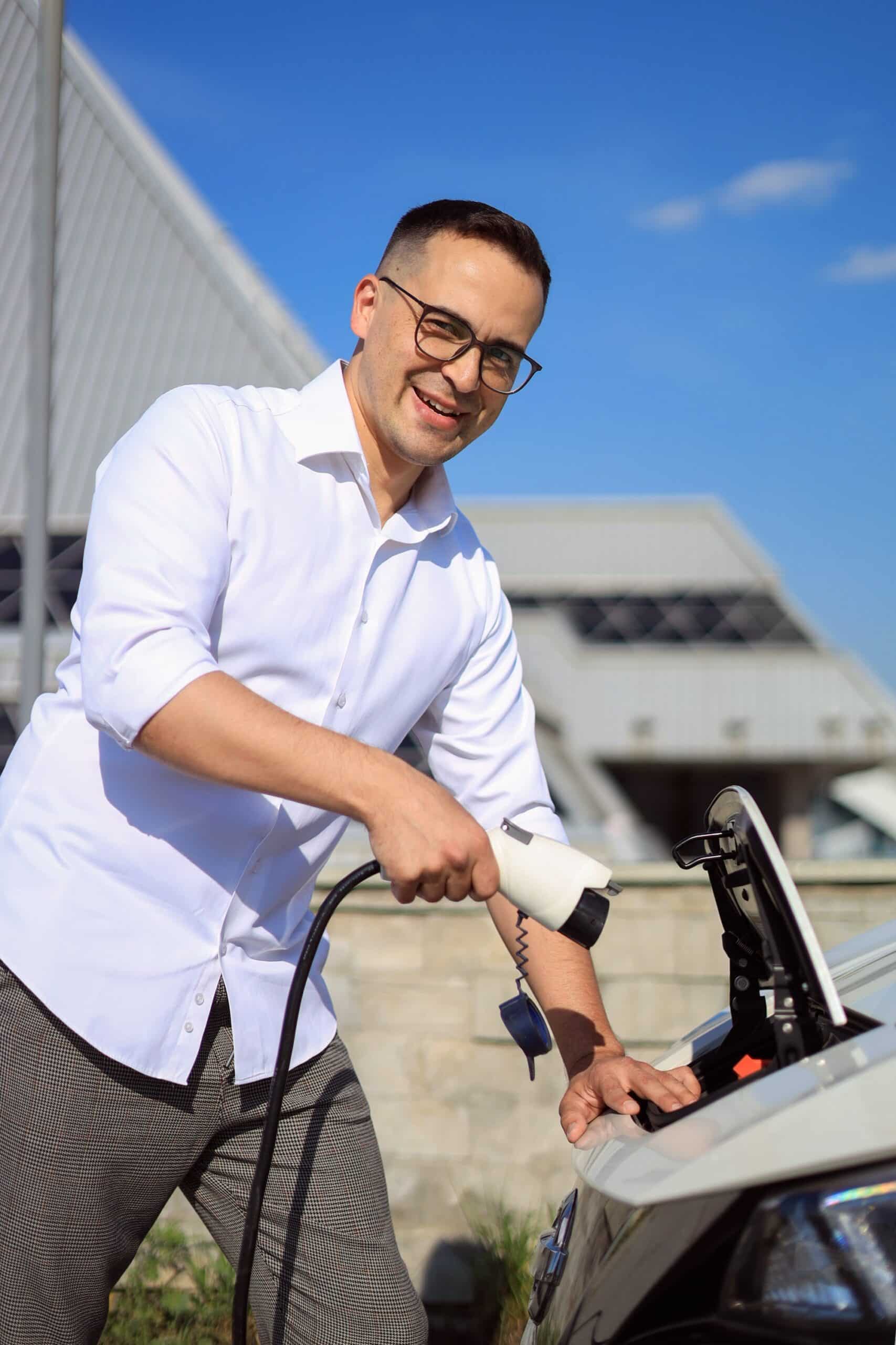 Lächelnder Mann lädt Auto mit Wallbox