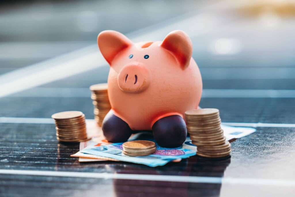 Sparschwein mit Geld auf Solarmodul