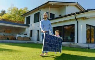 Vater und Tochter tragen Solarmodul im Garten