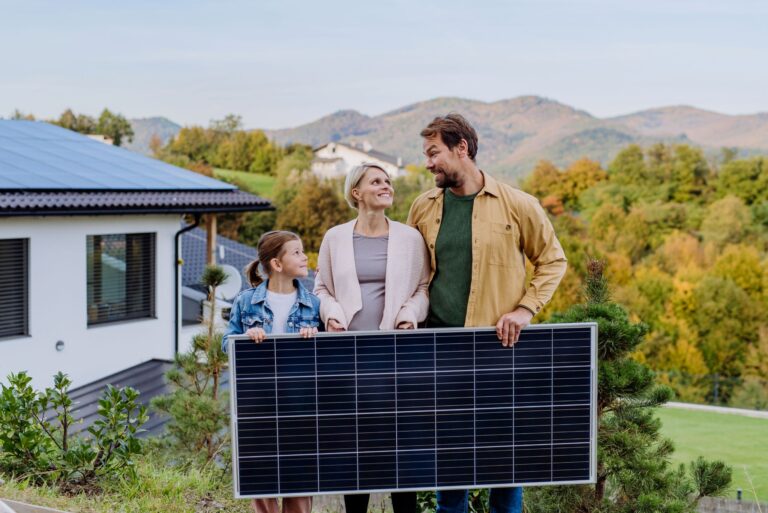 Familie mit Solarmodul vor Haus