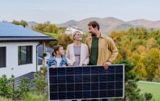 Familie mit Solarmodul vor Haus