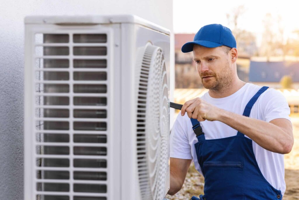 Techniker installiert Wärmepumpe vor Altbau