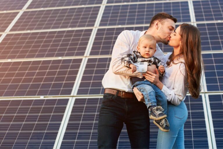 Paar mit Kleinkind küssen sich vor Solarmodulen, Symbolbild PV-Anlage anmelden