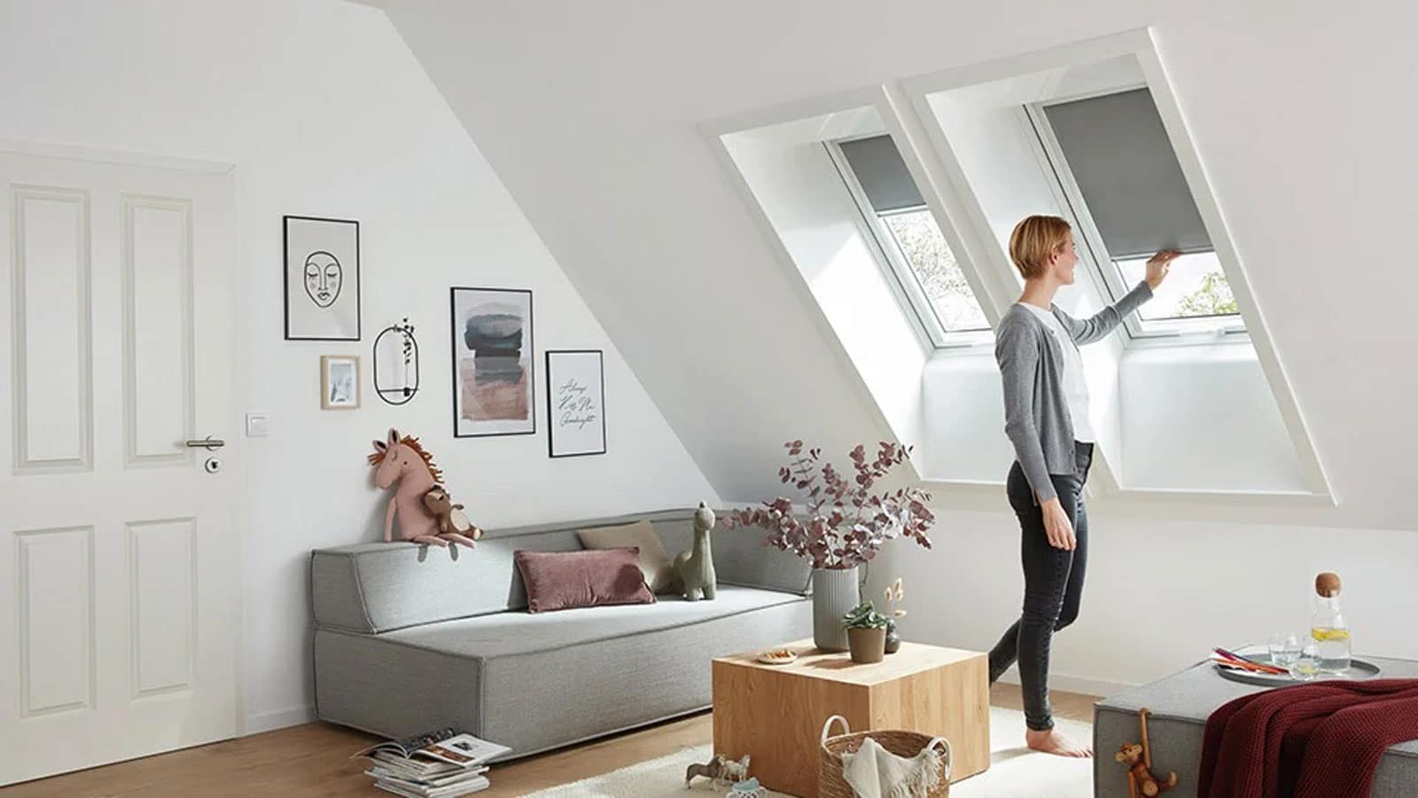 Person im Wohnzimmer zieht das Rollo eines Dachfensters